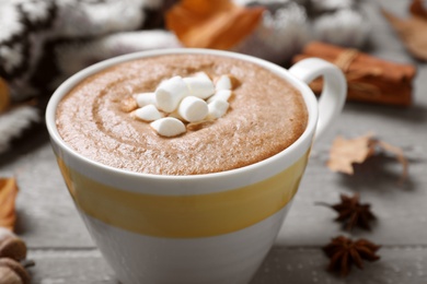 Cup of hot drink on grey wooden table, closeup. Cozy autumn atmosphere