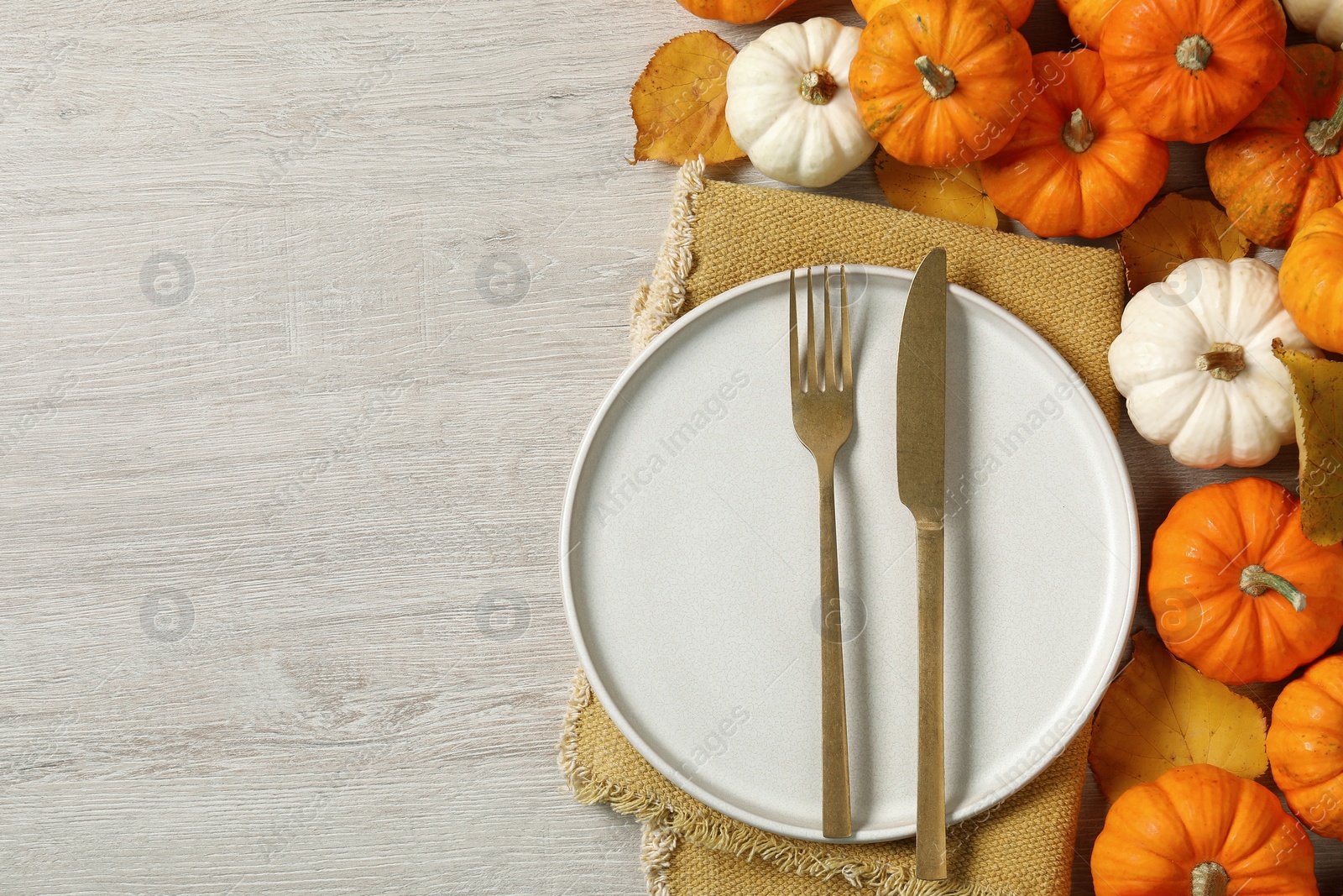 Photo of Happy Thanksgiving day. Beautiful table setting, autumn leaves and pumpkins on wooden background, flat lay with space for text