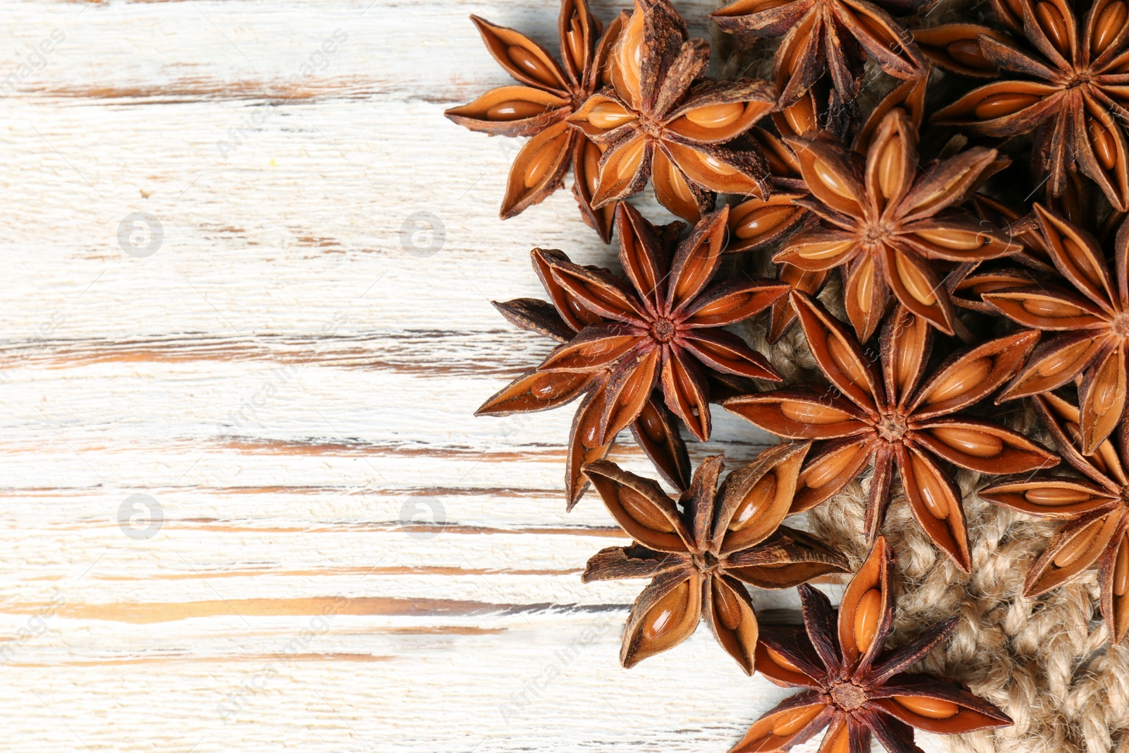 Photo of Many aromatic anise stars on white wooden table, flat lay. Space for text