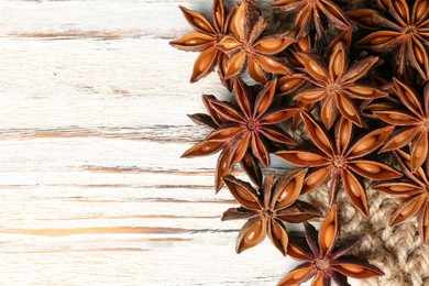 Photo of Many aromatic anise stars on white wooden table, flat lay. Space for text