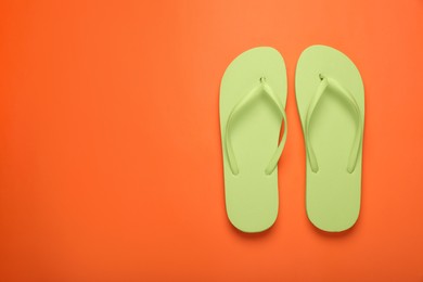 Photo of Stylish light green flip flops on orange background, top view. Space for text
