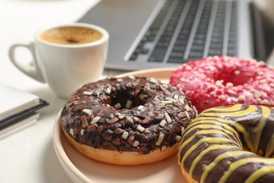 Photo of Bad eating habits at workplace. Sweet glazed donuts on white table, closeup