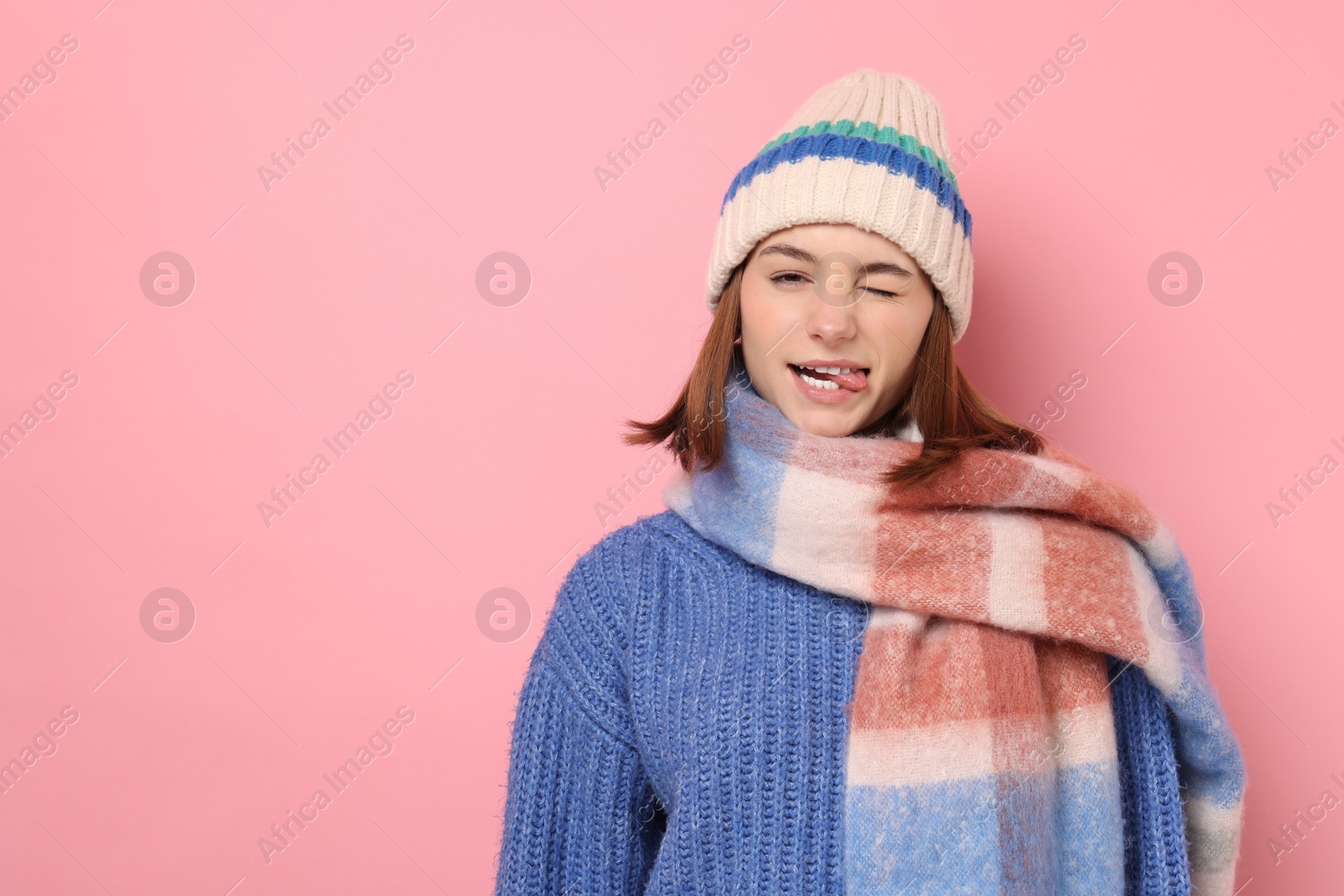 Photo of Beautiful woman in warm scarf and hat on pink background, space for text