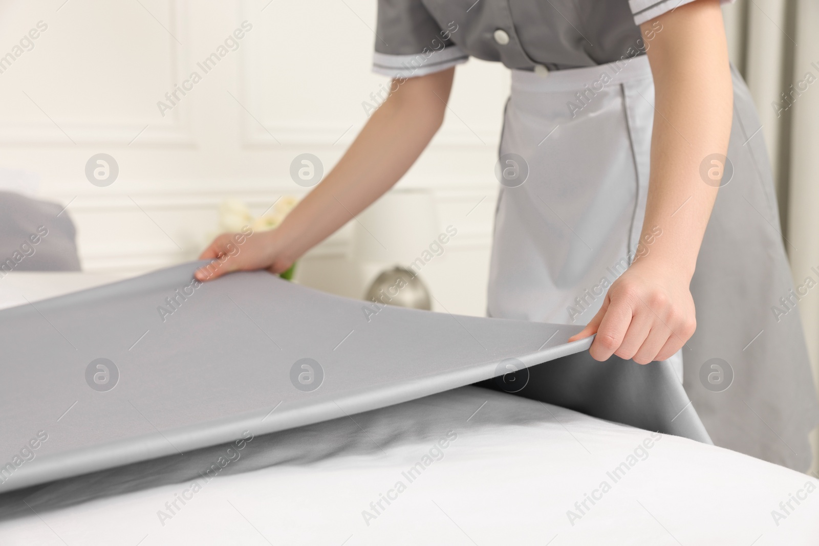 Photo of Maid making bed in hotel room, closeup