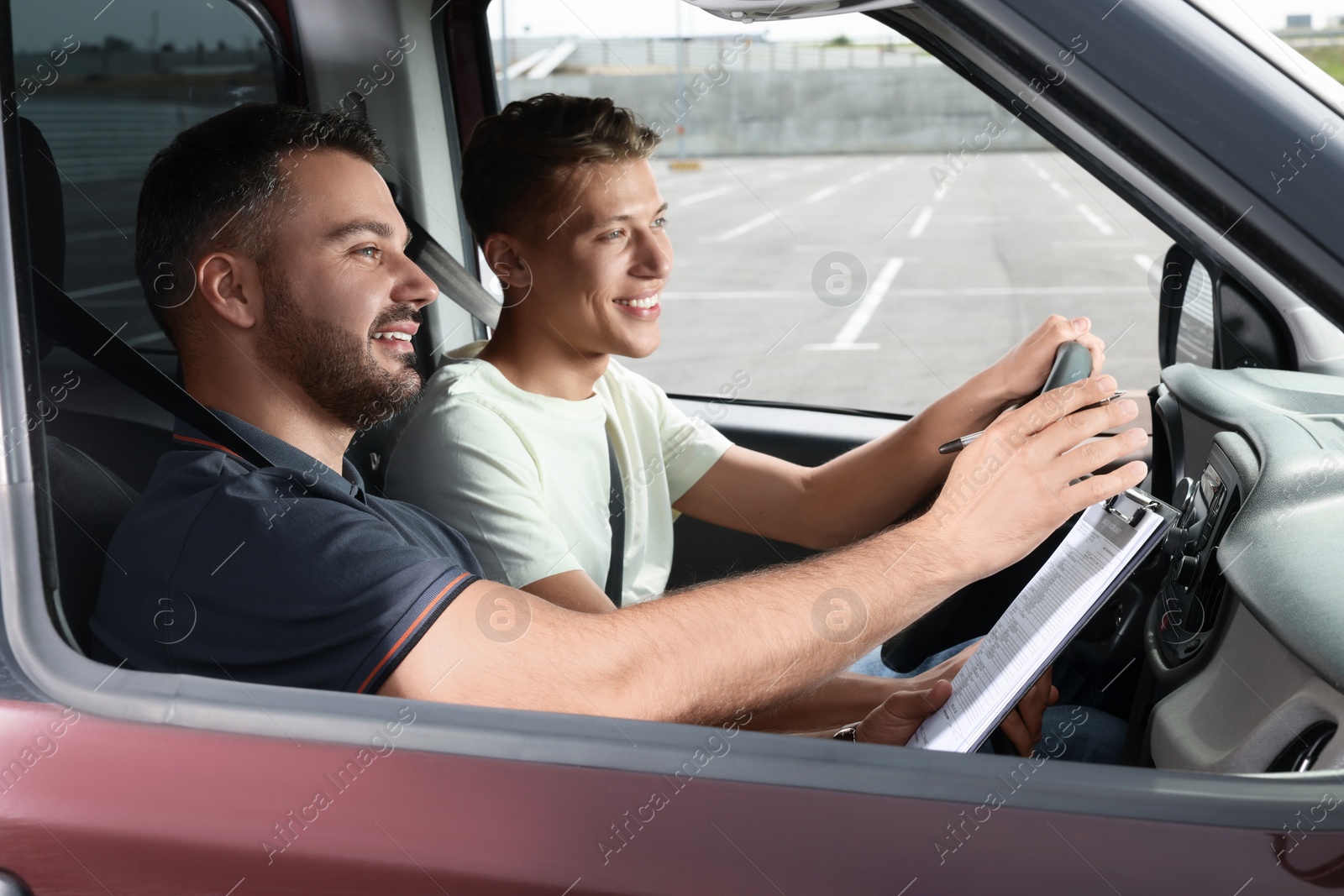 Photo of Driving school. Happy student passing driving test with examiner in car at parking lot