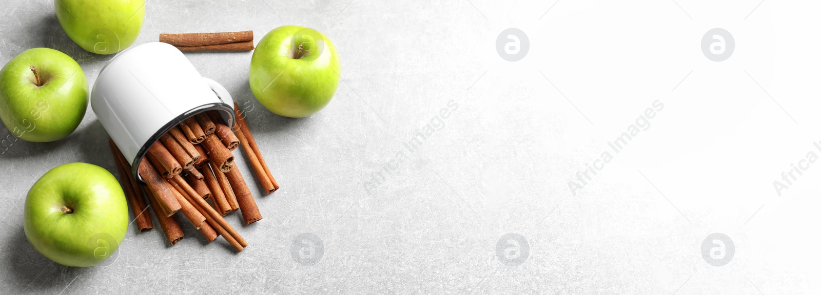 Image of Fresh apples and mug with cinnamon sticks on table, top view with space for text. Banner design