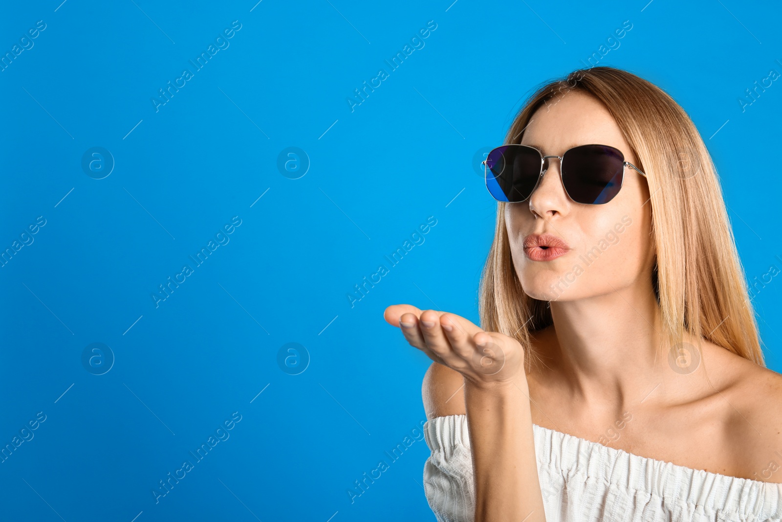 Photo of Beautiful woman in stylish sunglasses on light blue background, space for text