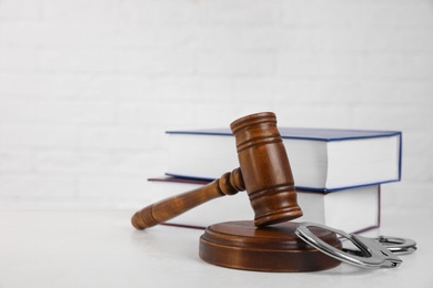 Gavel, handcuffs and books on table against white background, space for text. Criminal law