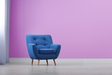 Photo of Stylish comfortable armchair near color wall