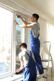 Professional workers tinting window with foil indoors