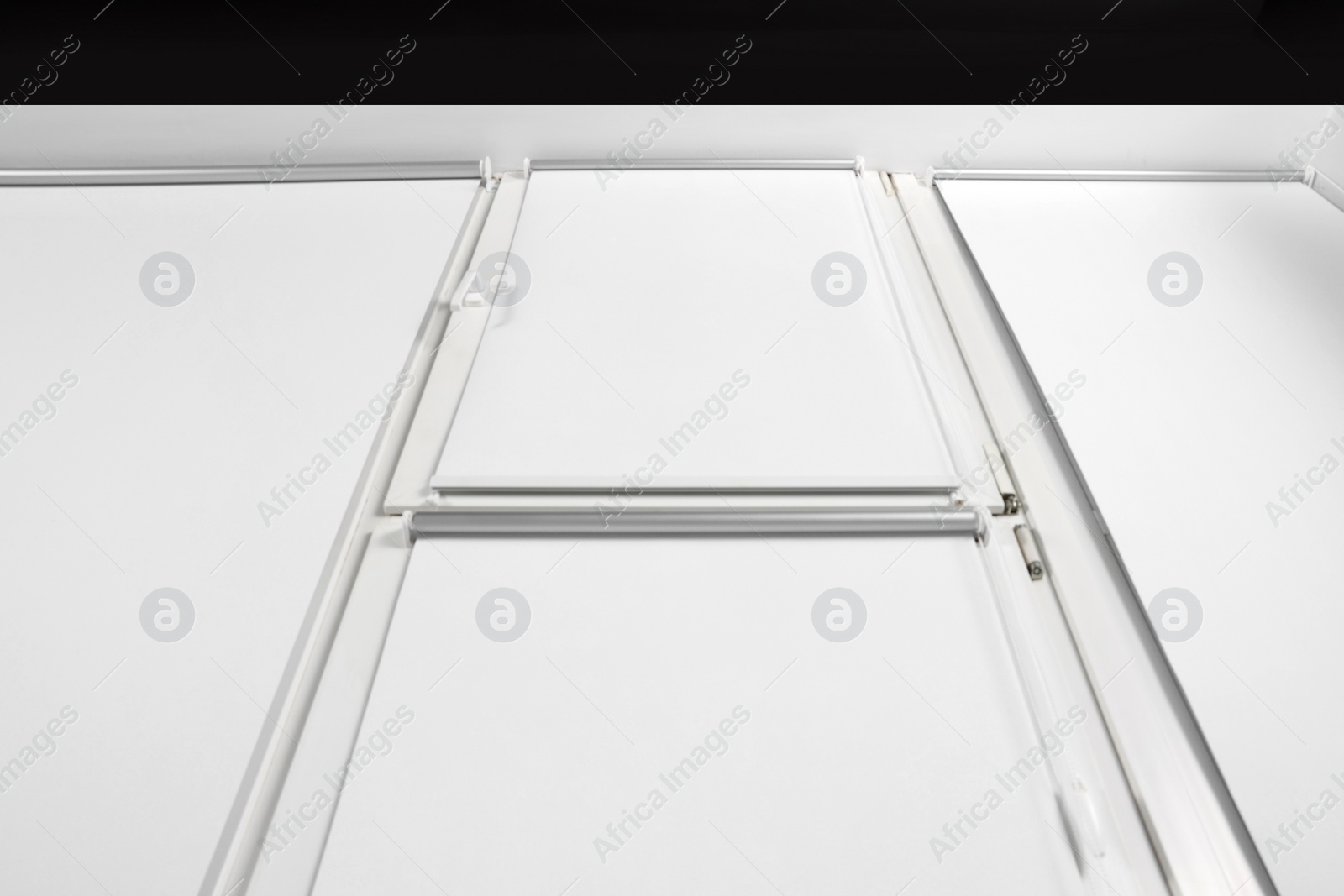 Photo of Window with closed white roller blinds indoors, low angle view