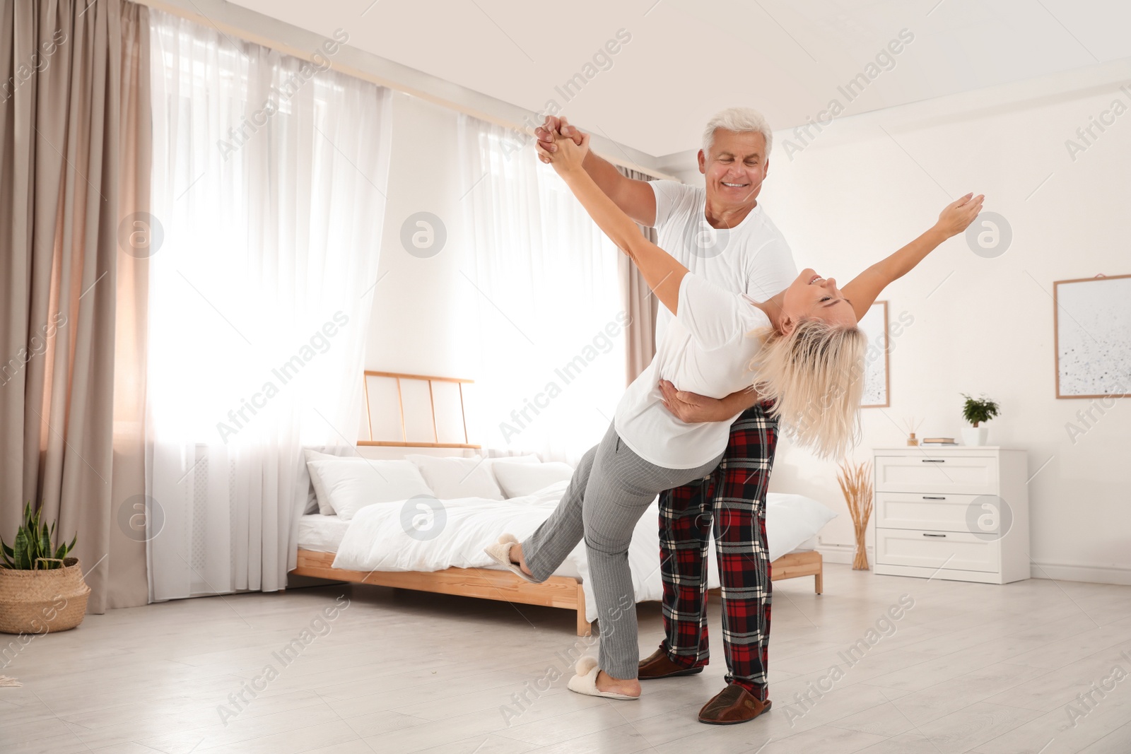 Photo of Happy mature couple dancing together in bedroom