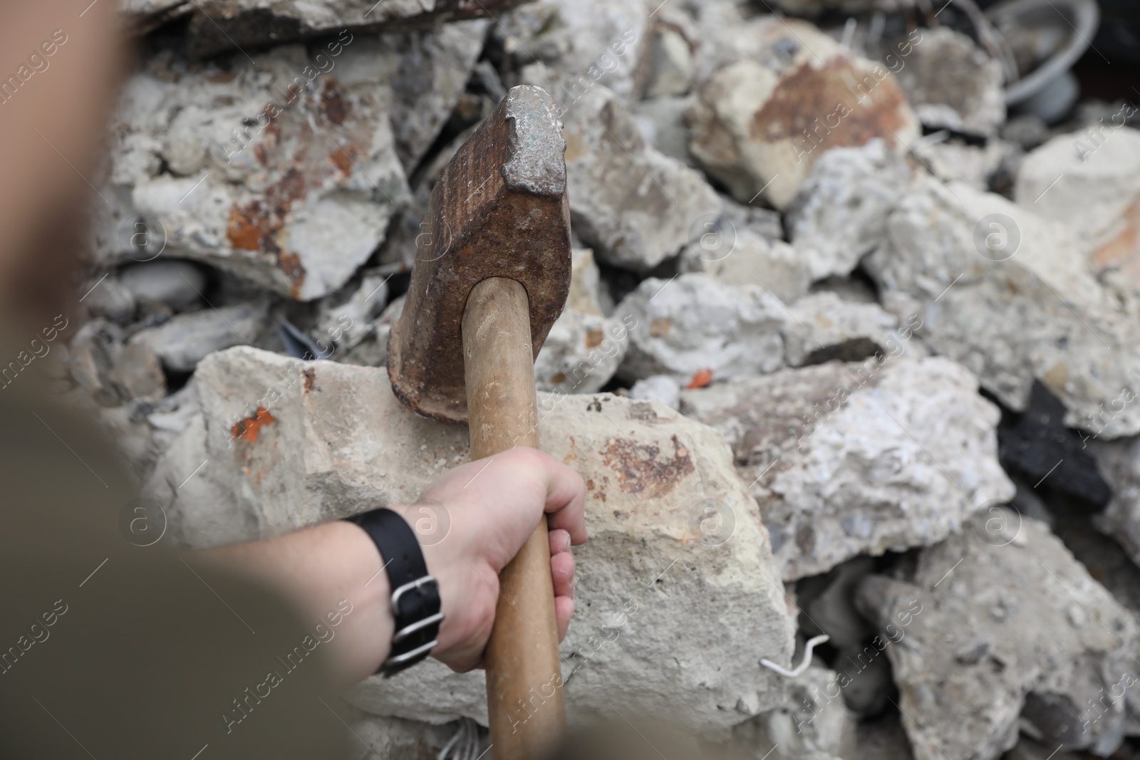 Photo of Man breaking stones with sledgehammer outdoors, closeup