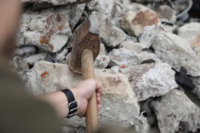 Photo of Man breaking stones with sledgehammer outdoors, closeup