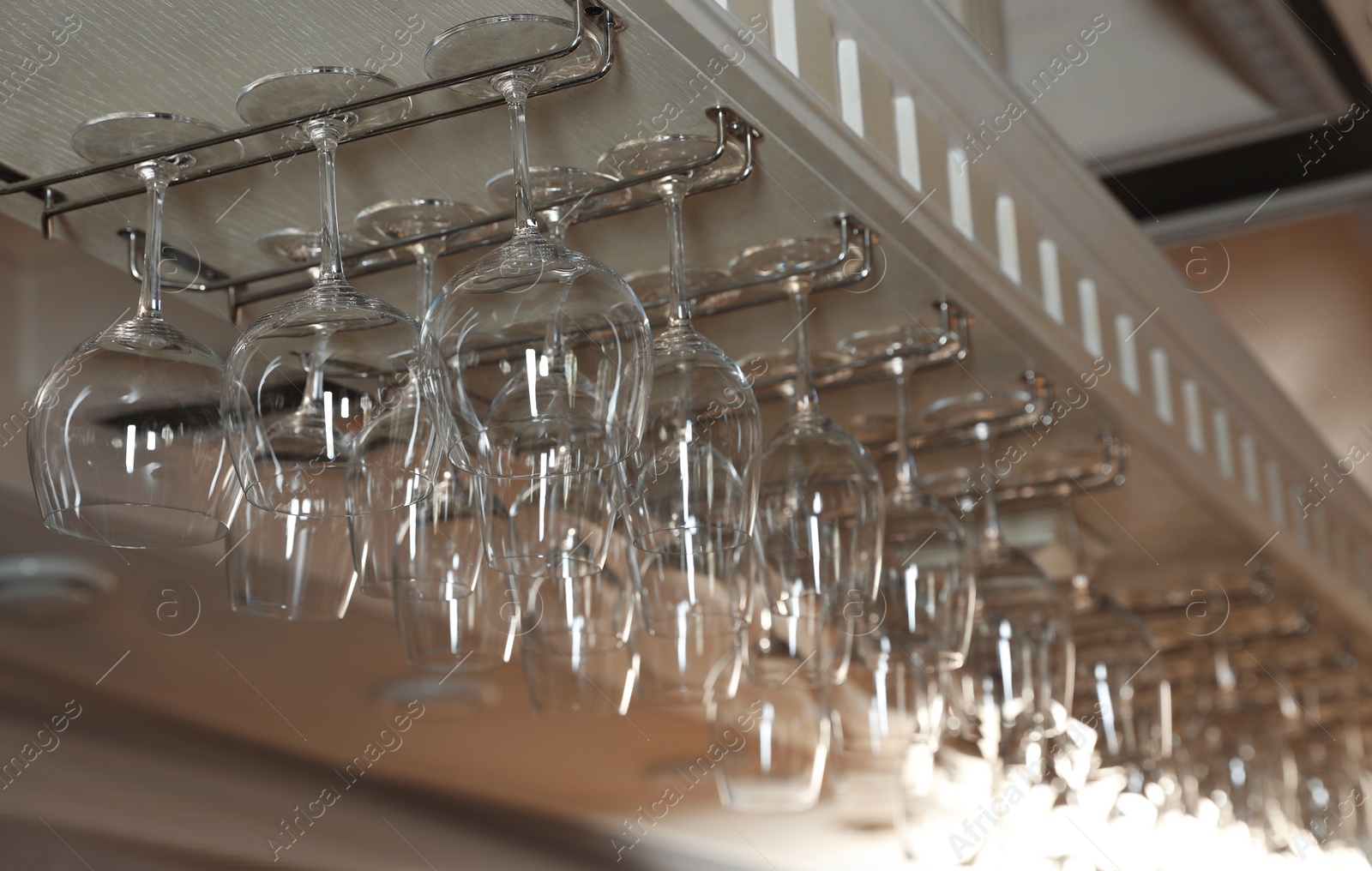 Photo of Set of empty clean glasses on bar racks