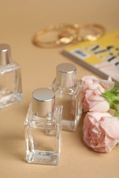 Photo of Perfumes and rose flowers on beige table