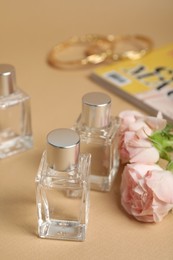 Perfumes and rose flowers on beige table