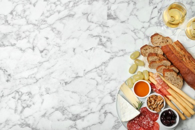 Flat lay composition with wine, snacks and space for text on marble background