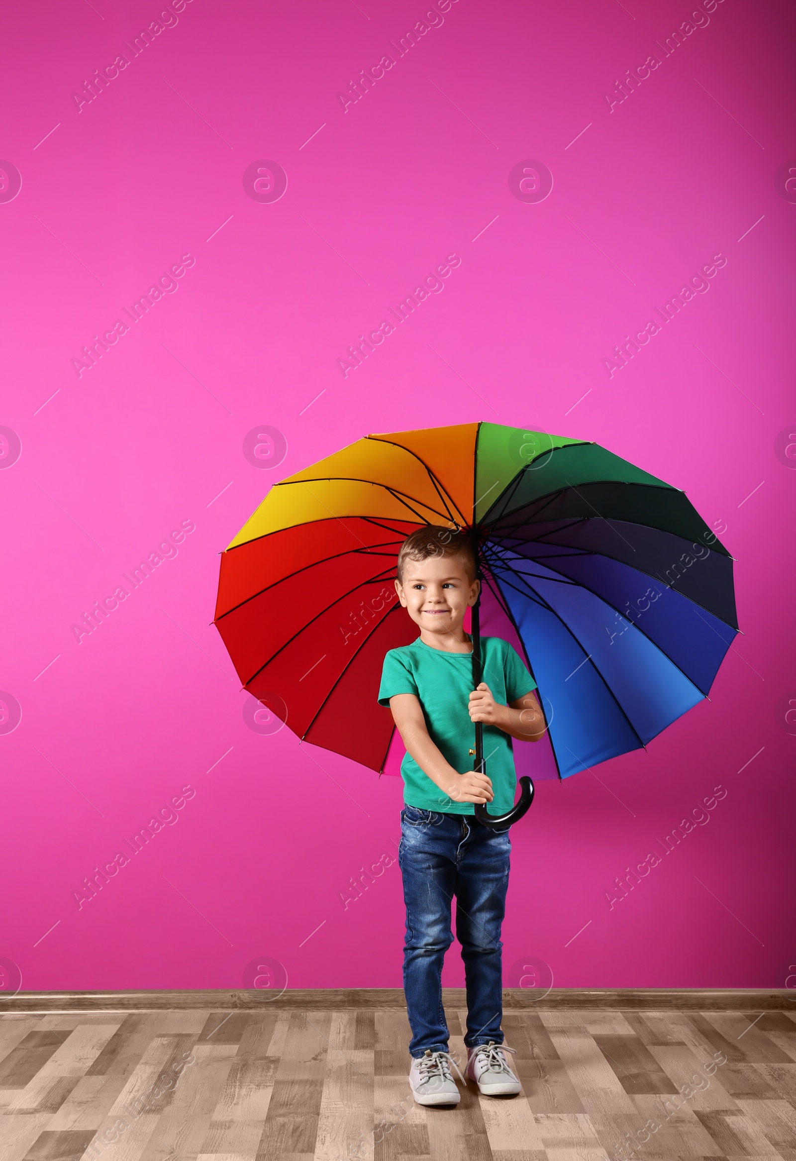 Photo of Little boy with rainbow umbrella near color wall