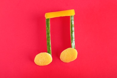 Photo of Musical note made of vegetables and fruits on color background, top view