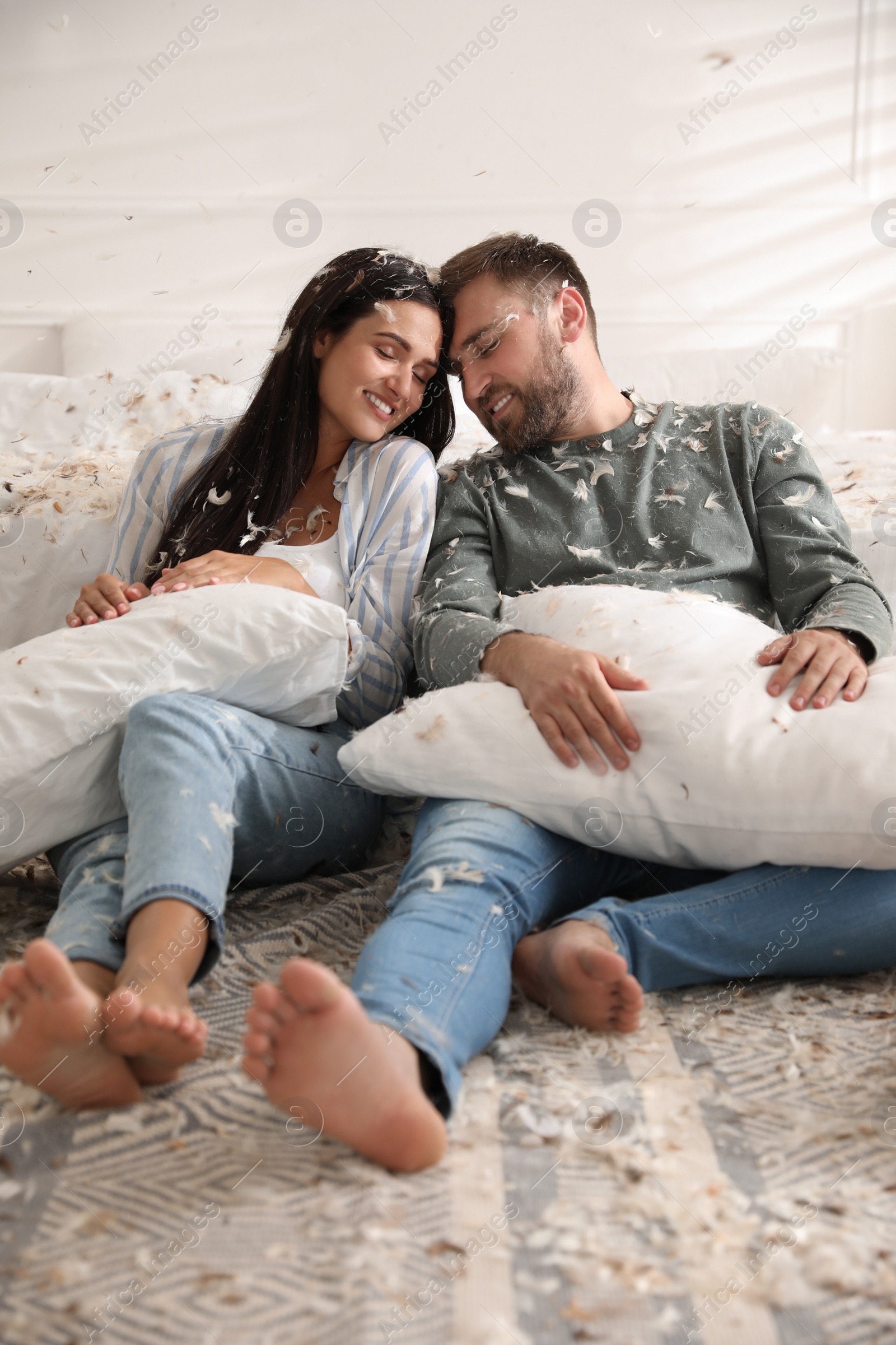 Photo of Happy young couple resting after fun pillow fight in bedroom