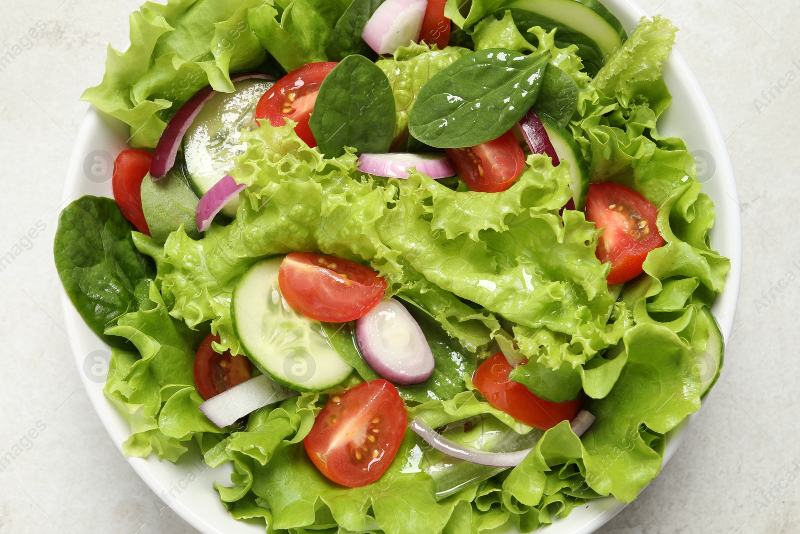 Photo of Delicious salad in bowl on light grey table, top view