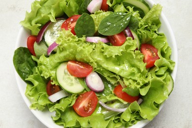 Delicious salad in bowl on light grey table, top view