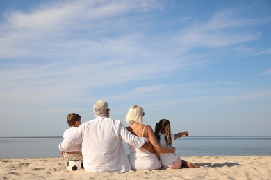 Photo of Cute little children with grandparents spending time together on sea beach, back view