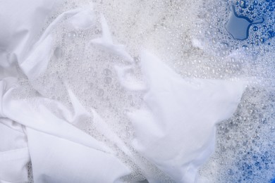 Photo of White garment in suds, closeup. Hand washing laundry