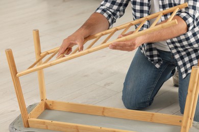 Man assembling furniture on floor indoors, closeup