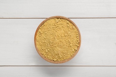 Photo of Bowl of aromatic mustard powder on white wooden table, top view