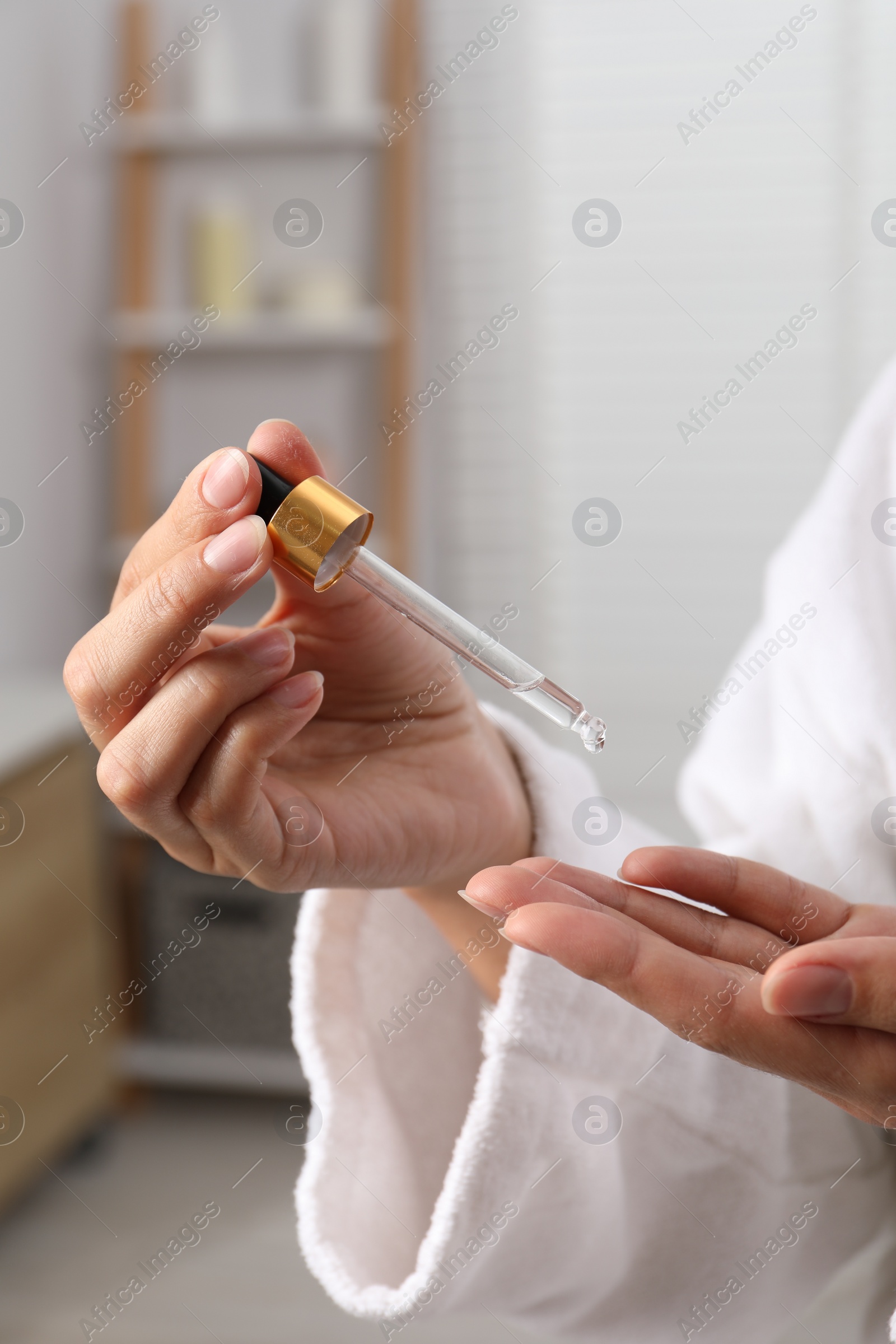 Photo of Woman applying cosmetic serum onto her hand indoors, closeup