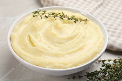 Photo of Bowl of tasty mashed potato with rosemary on grey marble table, closeup