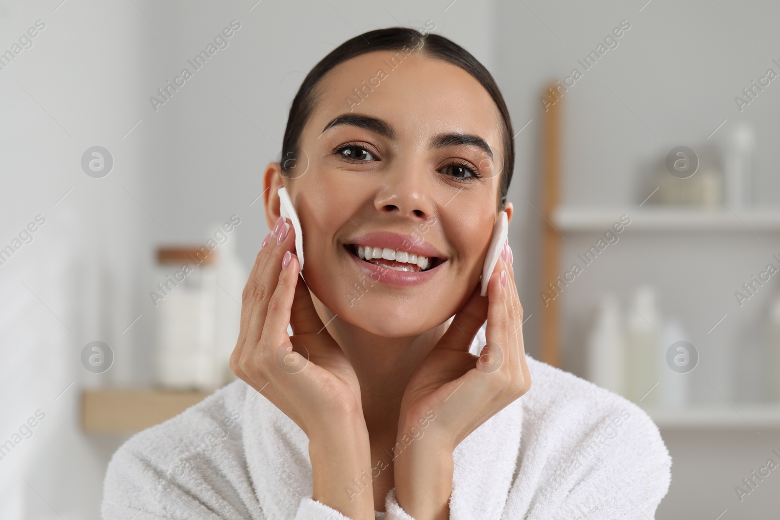 Photo of Beautiful woman removing makeup with cotton pads indoors