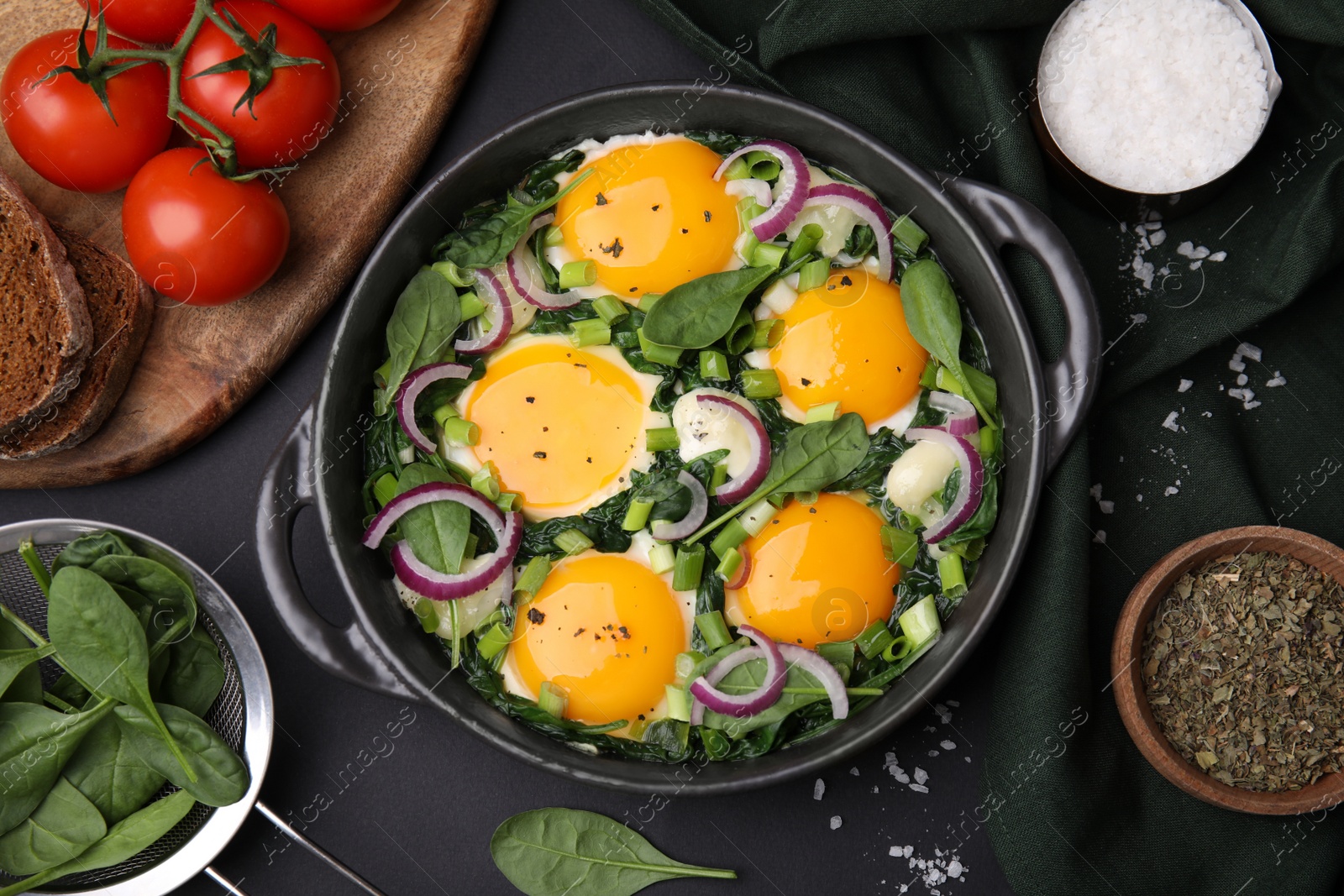 Photo of Flat lay composition with tasty Shakshouka and ingredients on black table