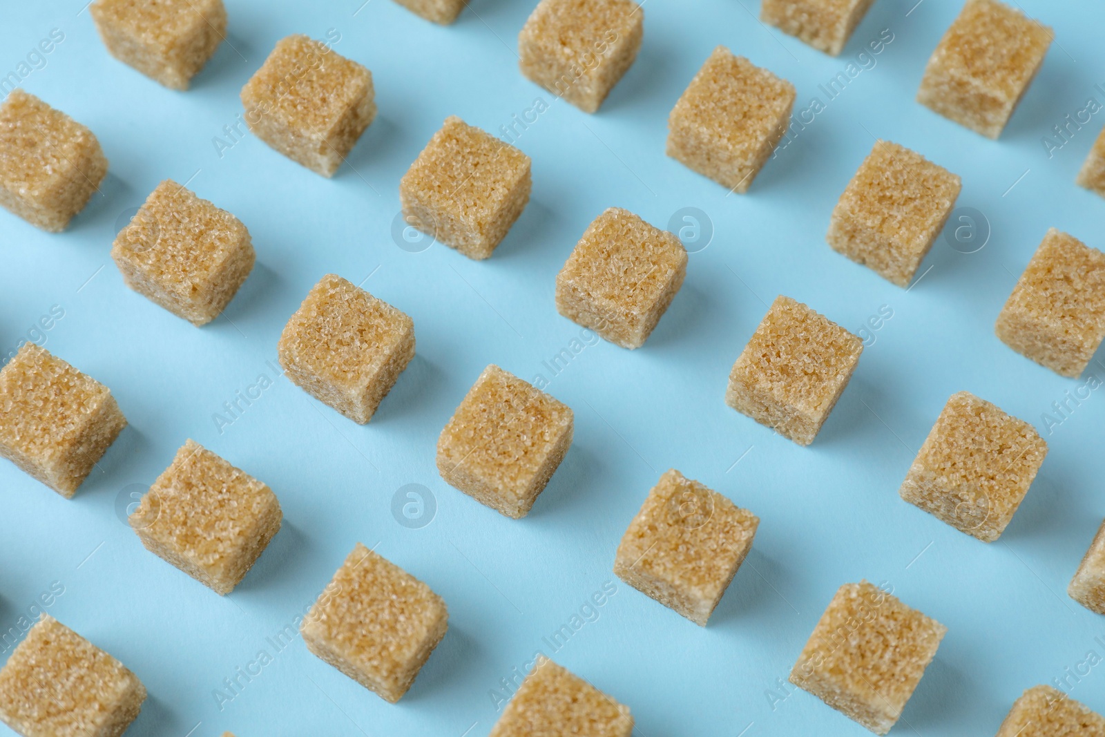 Photo of Brown sugar cubes on light blue background