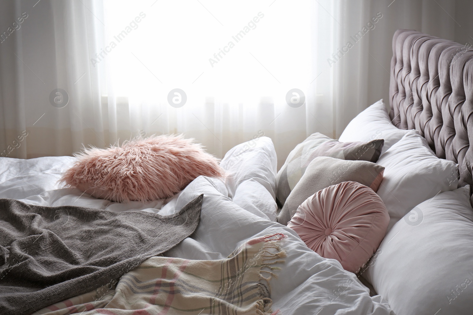 Photo of Comfortable bed with plaids and pillows in room