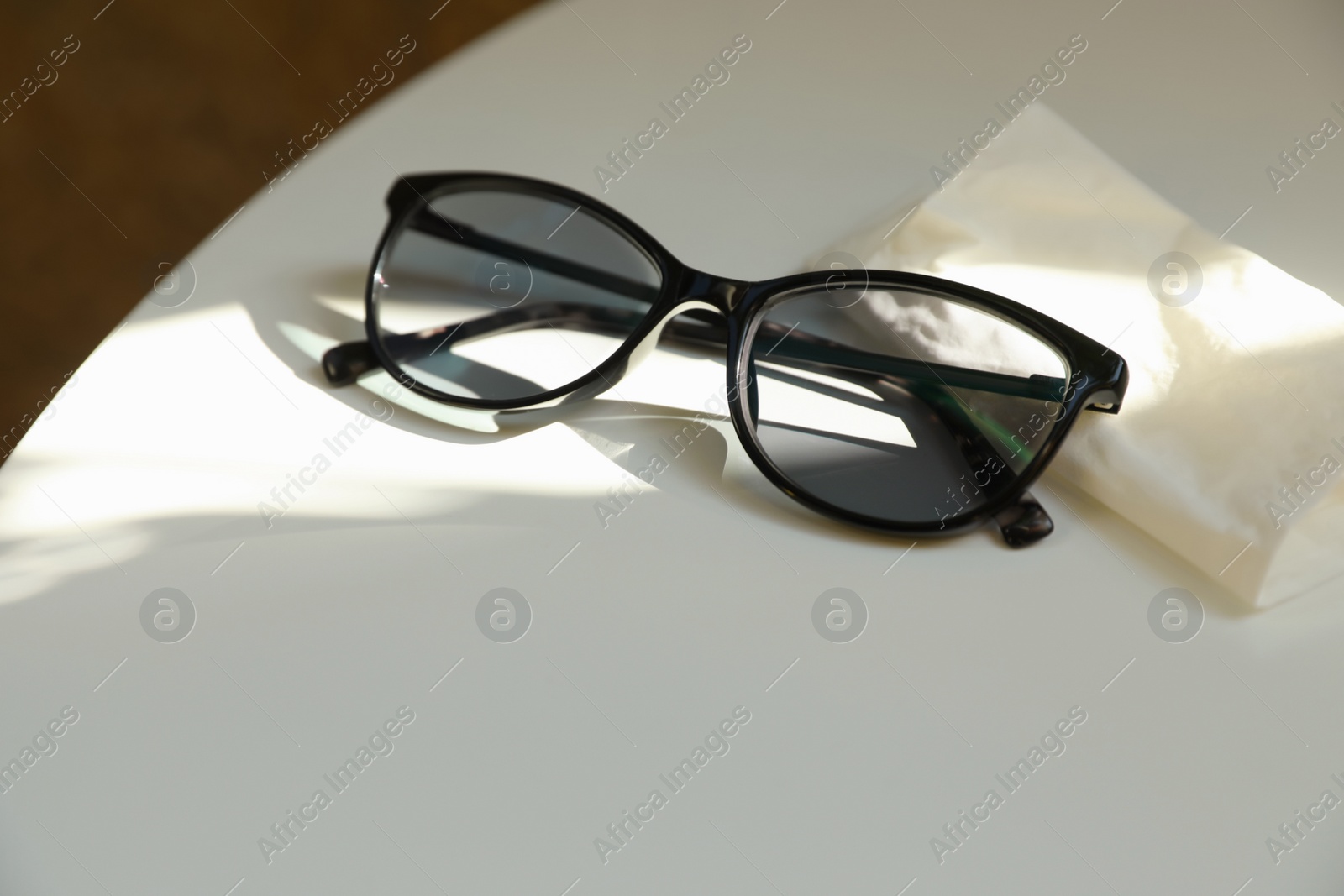 Photo of Stylish black eye glasses and cloth on white table. Space for text