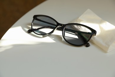 Photo of Stylish black eye glasses and cloth on white table. Space for text