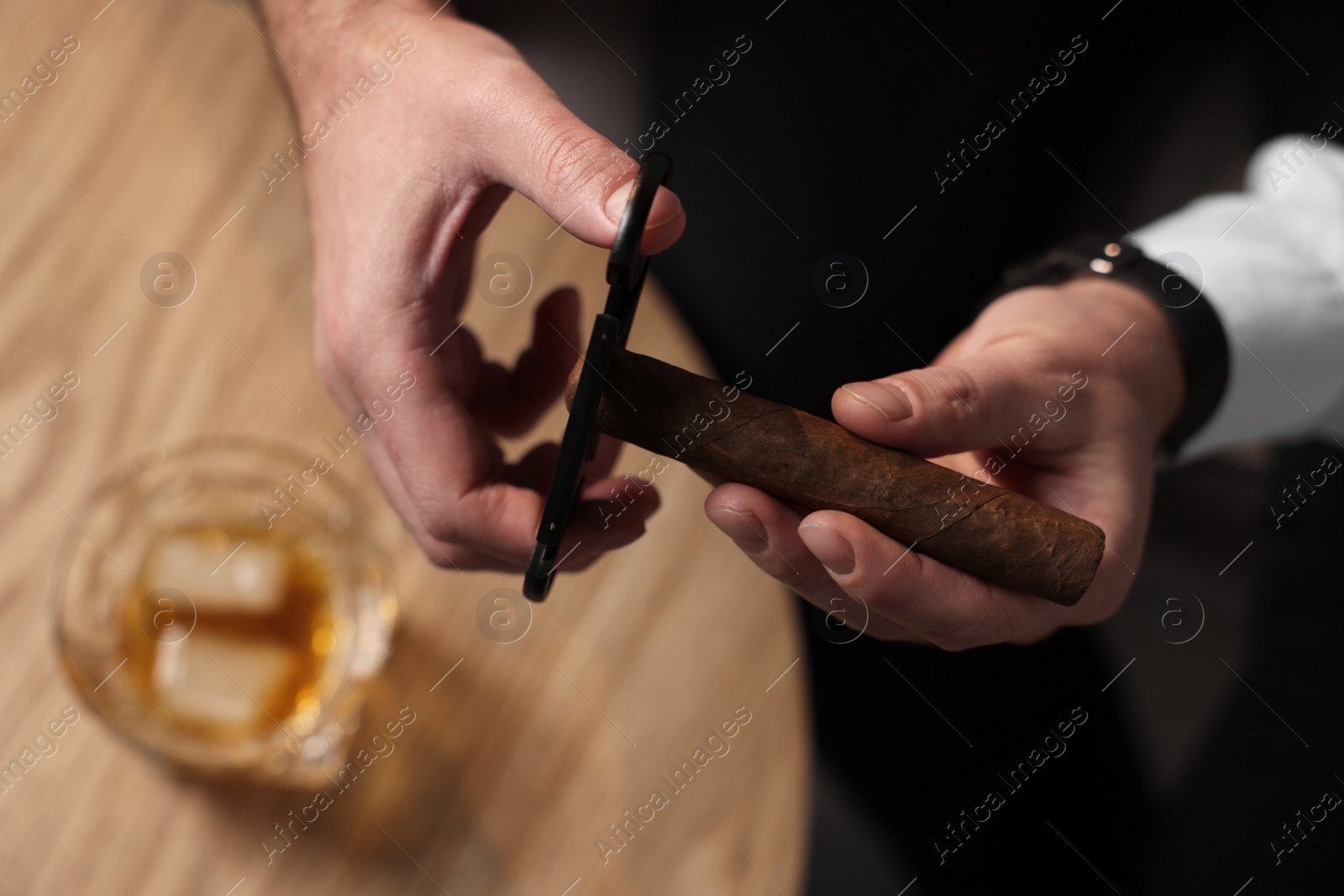 Photo of Man cutting tip of cigar over table, closeup