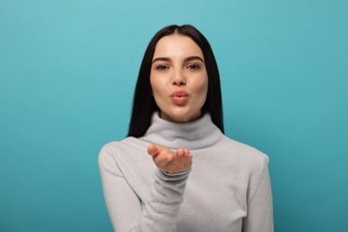 Photo of Beautiful young woman blowing kiss on light blue background