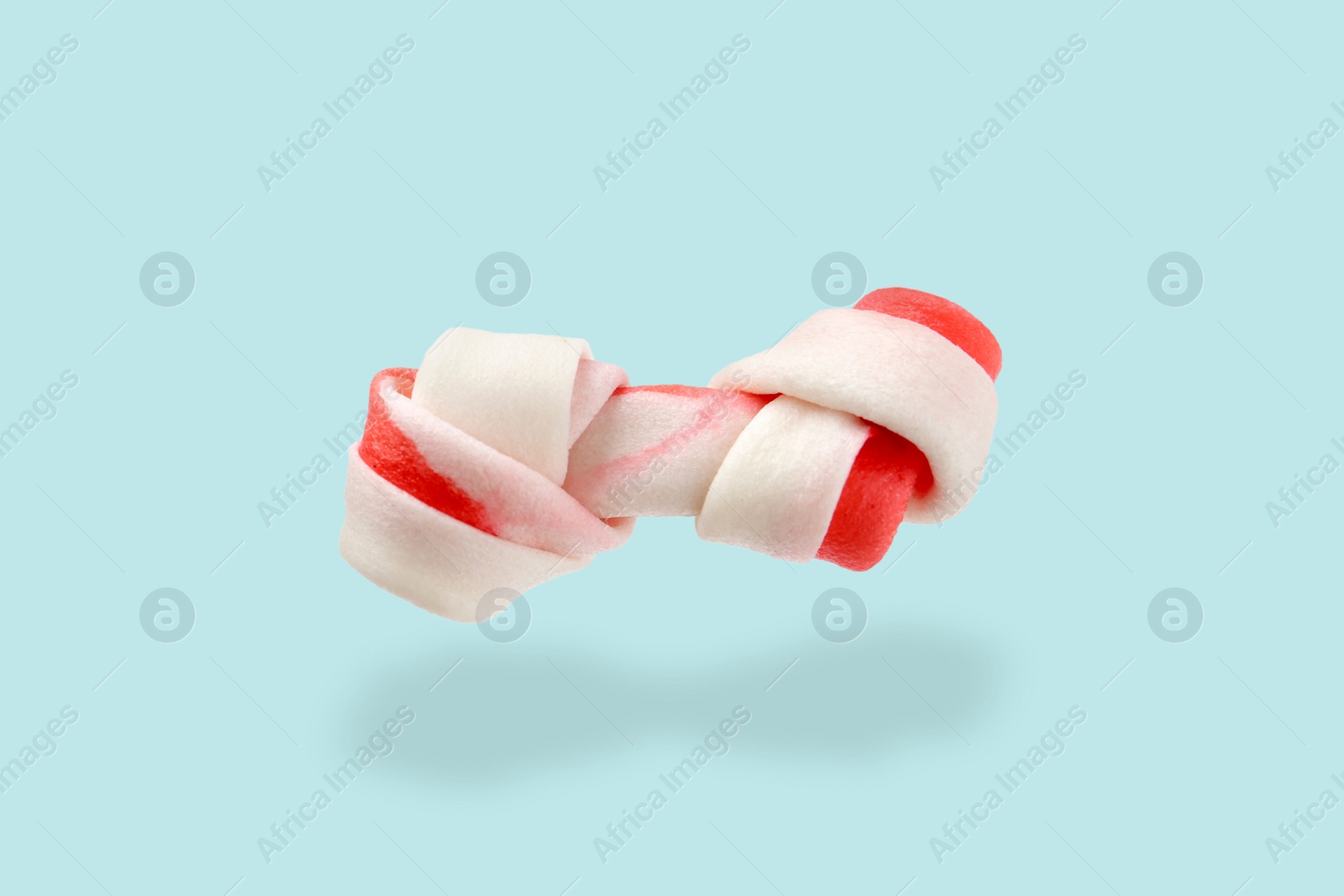 Image of Bone dog treat in air on light blue background