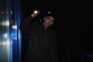 Photo of Male security guard with flashlight in dark corridor