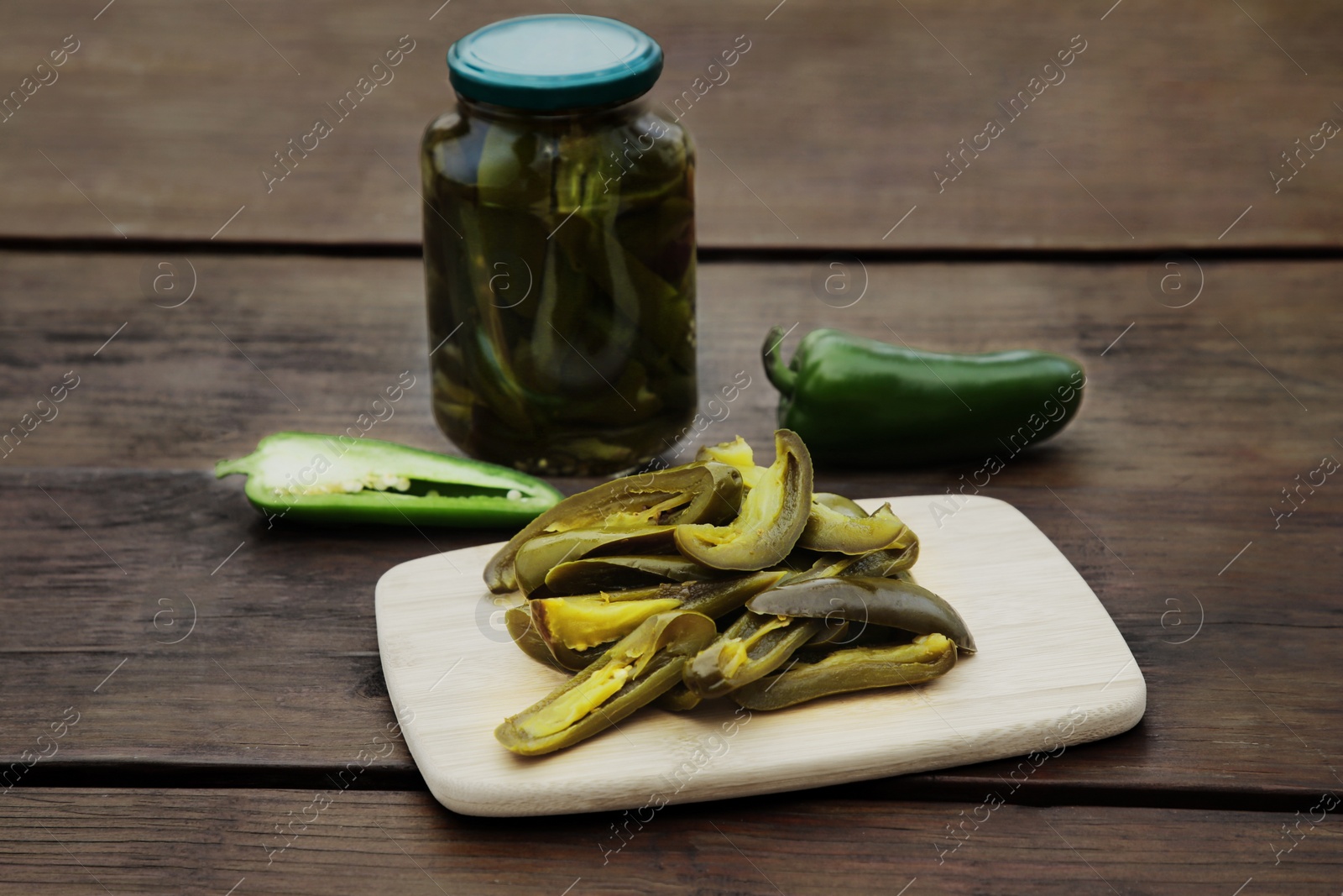 Photo of Fresh and pickled green jalapeno peppers on wooden table