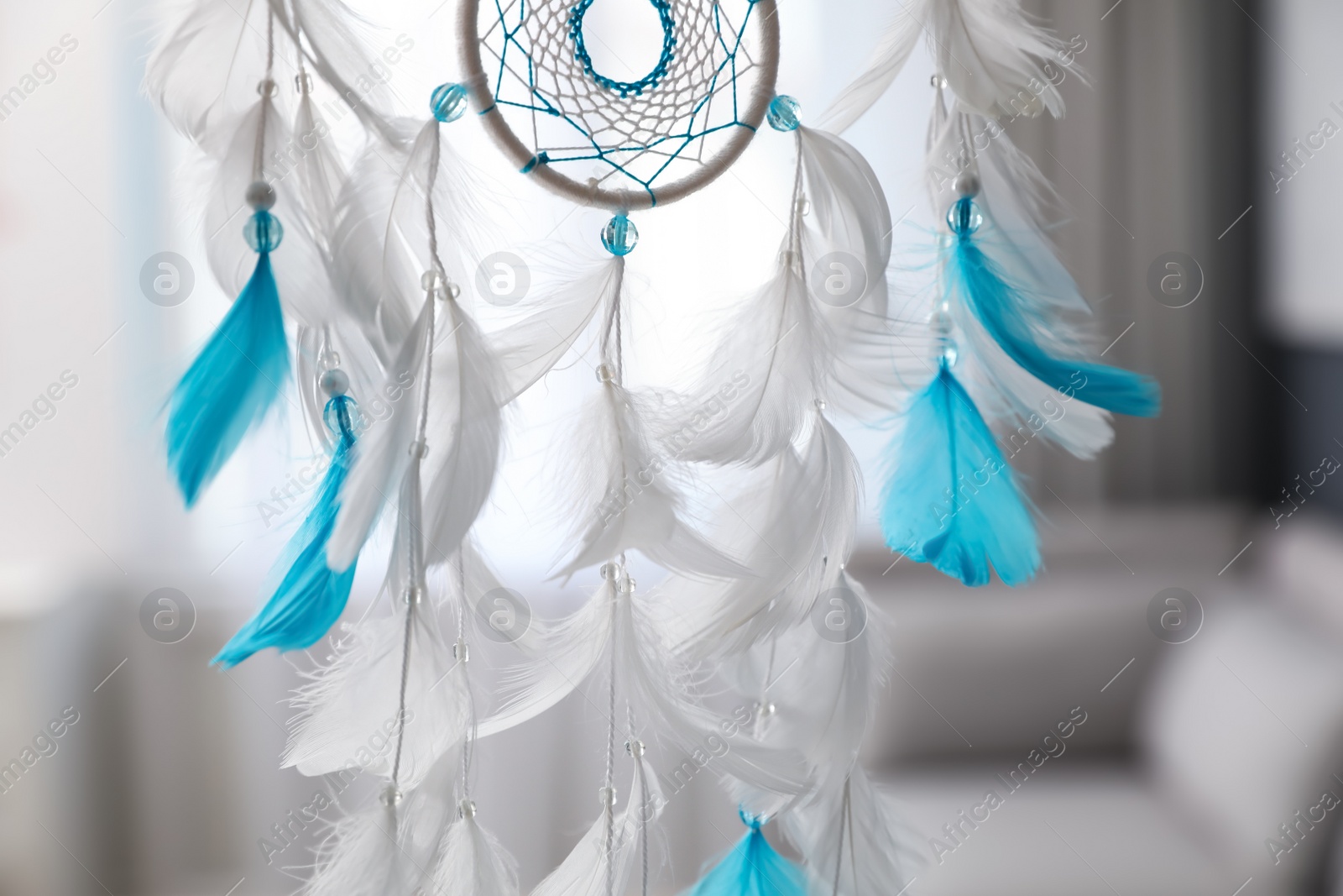 Photo of Beautiful dream catcher hanging against blurred background, closeup