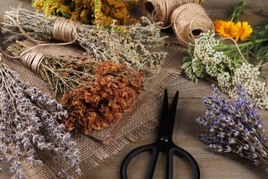 Photo of Different herbs, thread and scissors on wooden table