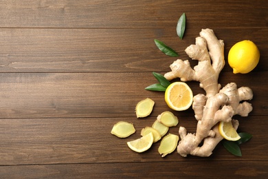 Photo of Fresh lemons and ginger on wooden table, flat lay. Space for text