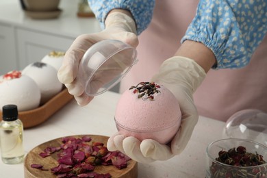 Woman in gloves with self made bath bomb at white table indoors, closeup
