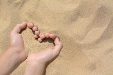Photo of Child holding sand in hands outdoors, closeup with space for text. Fleeting time concept
