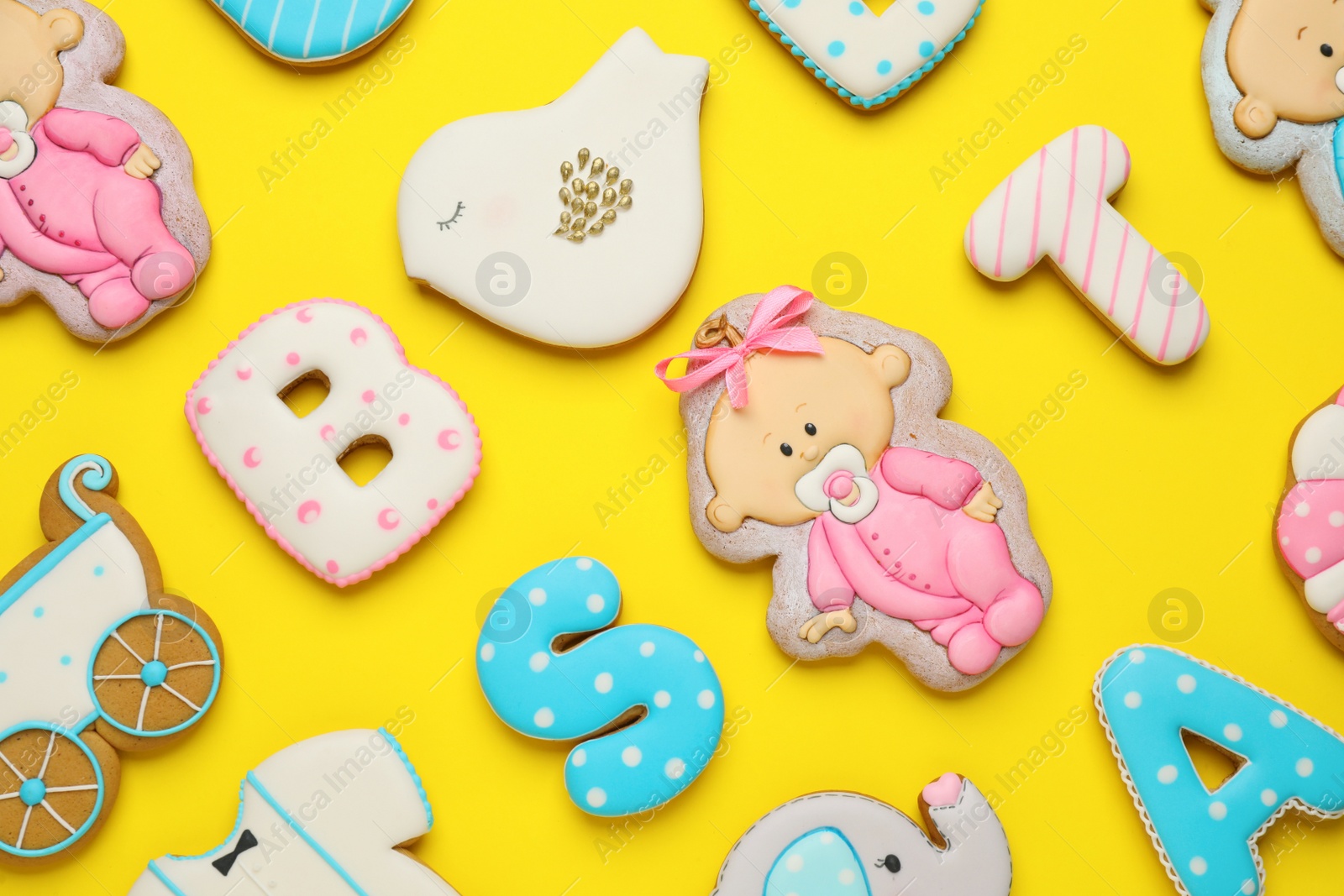 Photo of Set of baby shower cookies on yellow background, flat lay